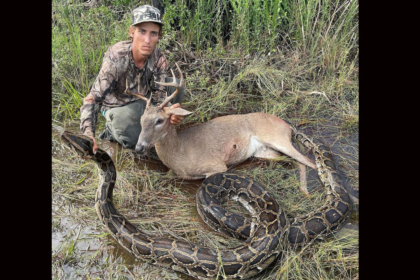 A hunter poses with a buck and a python taken on the same day during a Florida hunt.