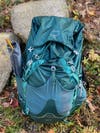teal osprey backpack laying on the ground
