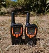 A pair of Cobra ACTX345 Walkie Talkies sitting on the grass