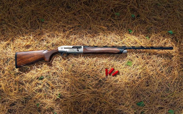 The new Beretta A400 28-gauge shotgun lying among pine needles whith shotgun shells.