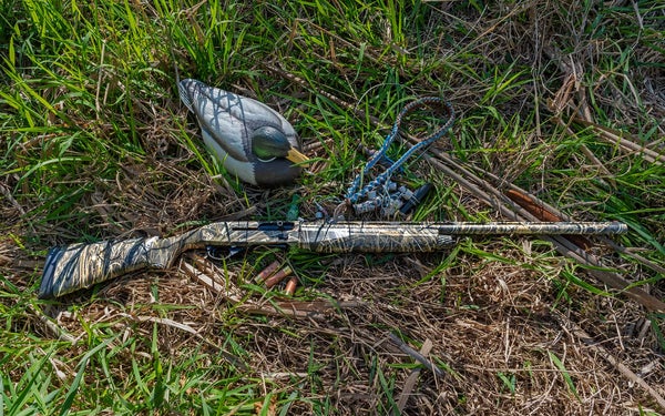 The new Stoeger M3000 lying among marsh grasses with duck decoy nearby.