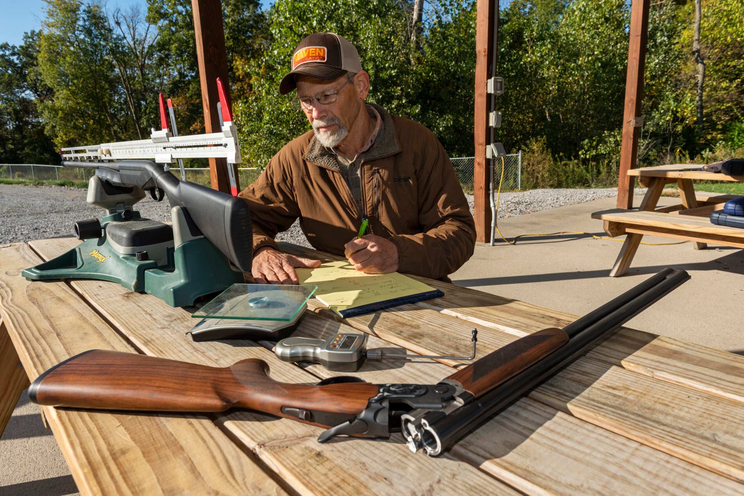 Field & Stream shotguns editor sits at ta table, taking evaluation notes on two test shotguns.