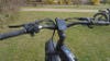 The black handlebars of an electric bike against a grassy background. 