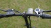 The handlebars and controls of an Ecotric fat tire bike against a green grass background. 