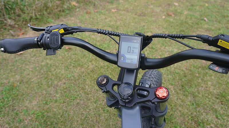 The handlebars of the Engwe X24 electric bike above a grass lawn. 
