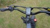 The handlebars of the Engwe X24 electric bike above a grass lawn. 