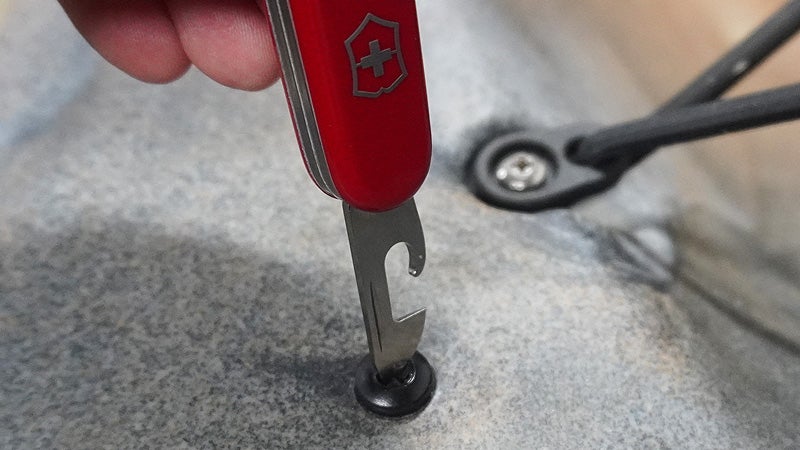 A red Swiss Army knife recruit with the screwdriver tool extended in a Phillips head screw. 