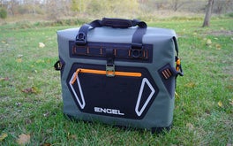 A gray and orange Engel HD30 cooler sitting on a grassy lawn.