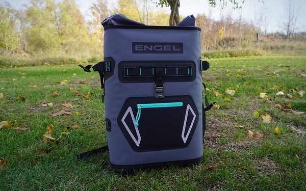 A gray, black, and teal Engel Roll Top backpack cooler on a grassy lawn.