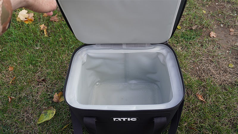 The interior of the black RTIC soft pack cooler on a grassy lawn. 