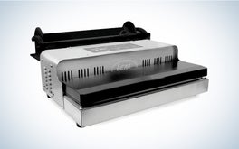 A silver and black LEM commercial grade vacuum sealer on a black and white gradient background.