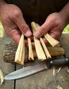 Different sizes of wood for learning how to start a campfire are shown alongside a knife.