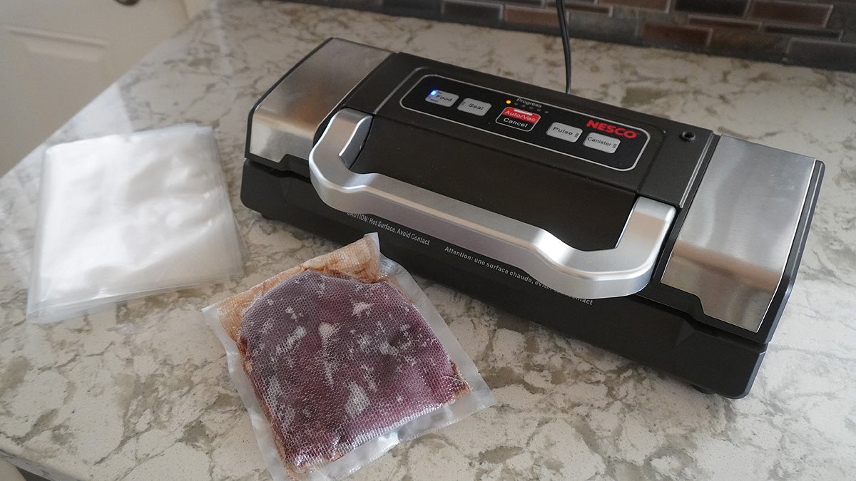 A Nesco VS-09 vacuum sealer on a black and white gradient background.
