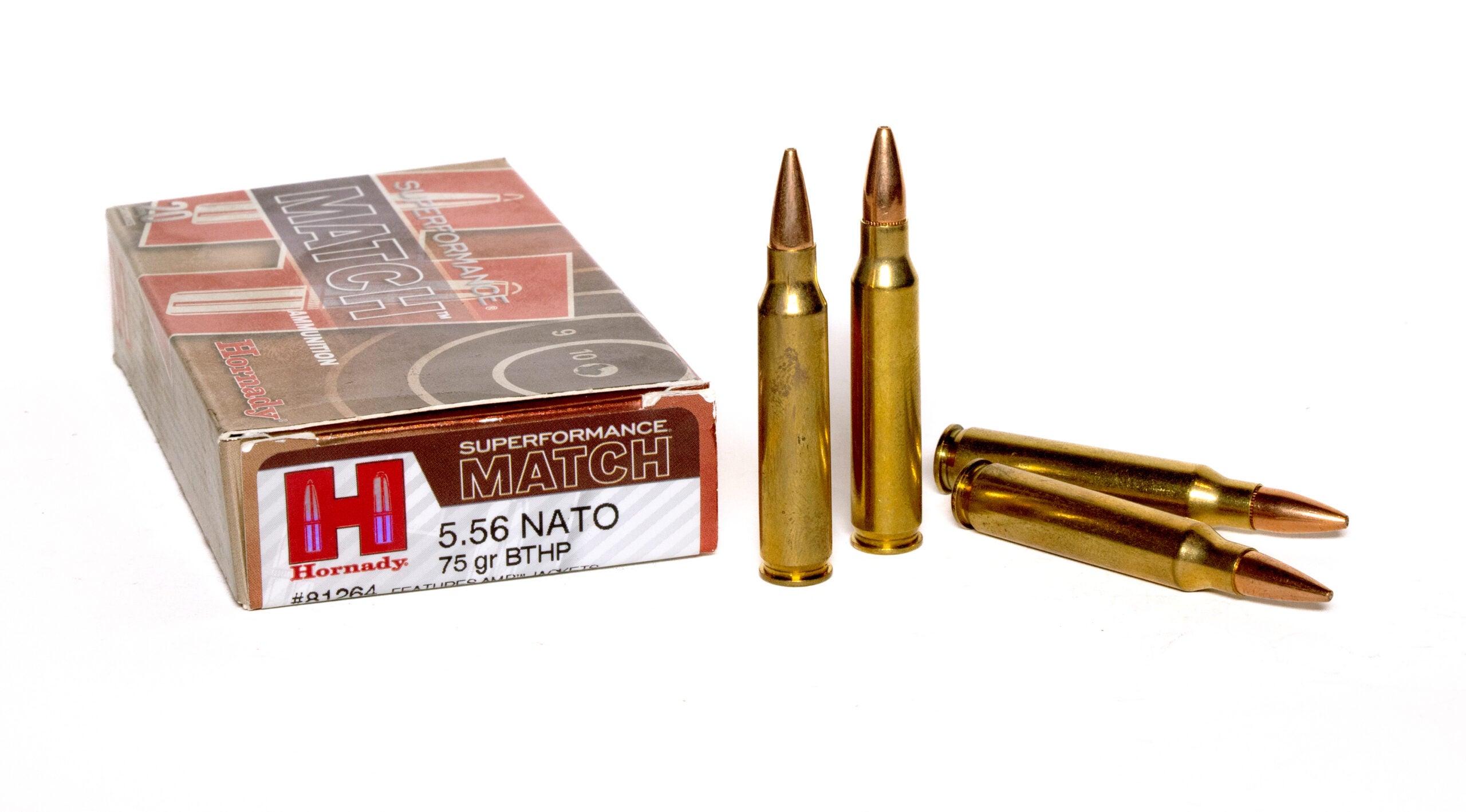 A box of 556 Nato ammo on a white table with four cartridges next to it.