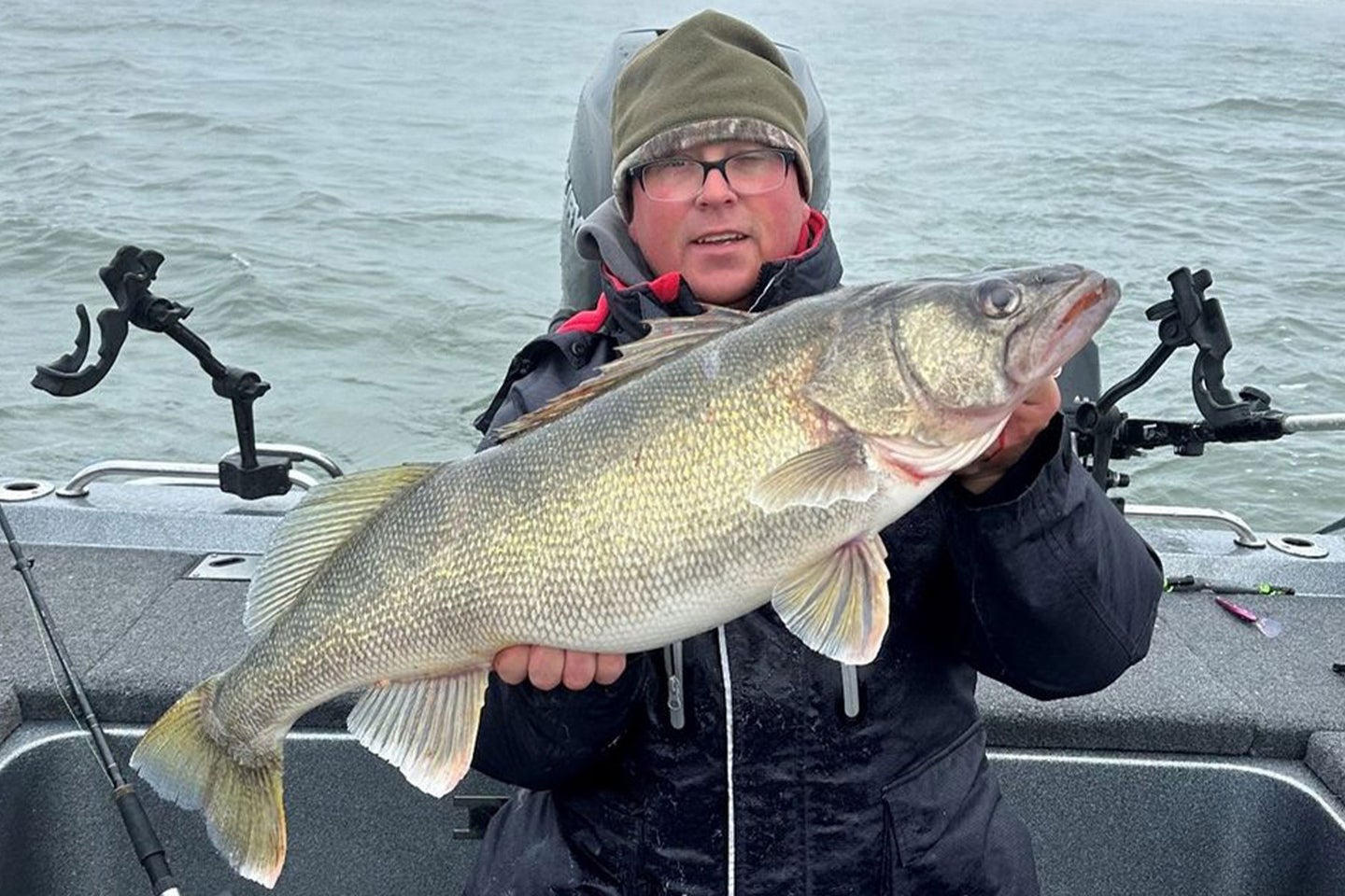 An angler poses with a state-record walleye in a fishing boat.