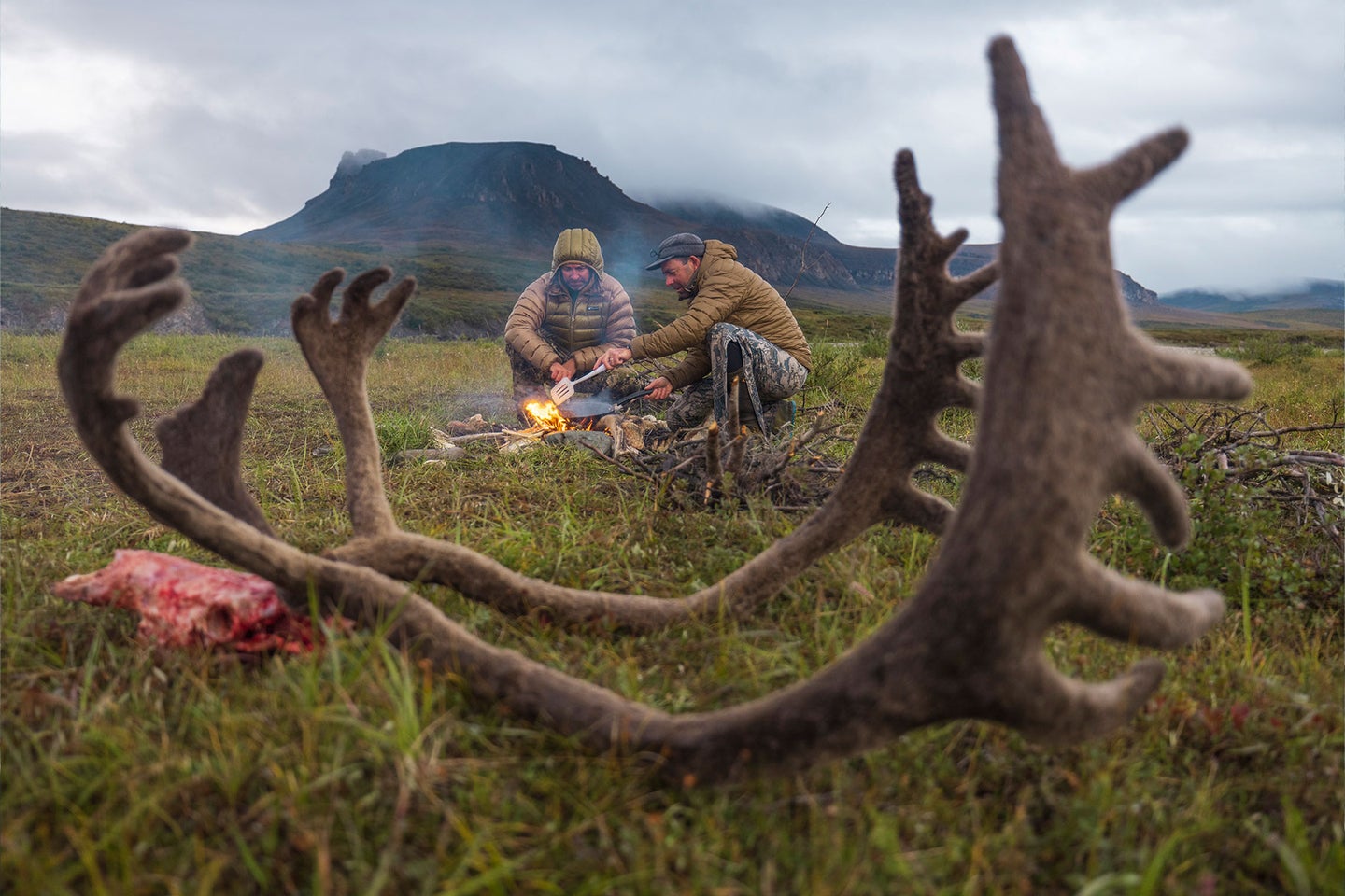 A pair of hunters enjoy freshly harvested caribou meat in Alaska's Brooks Range.