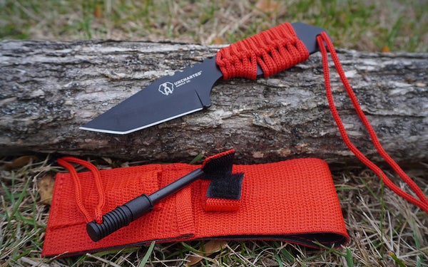 A red Uncharted Supply Co knife on a grey bark log.