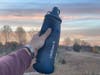 Female hiker holding LifeStraw Peak Series Collapsible Squeeze Bottle with Filter