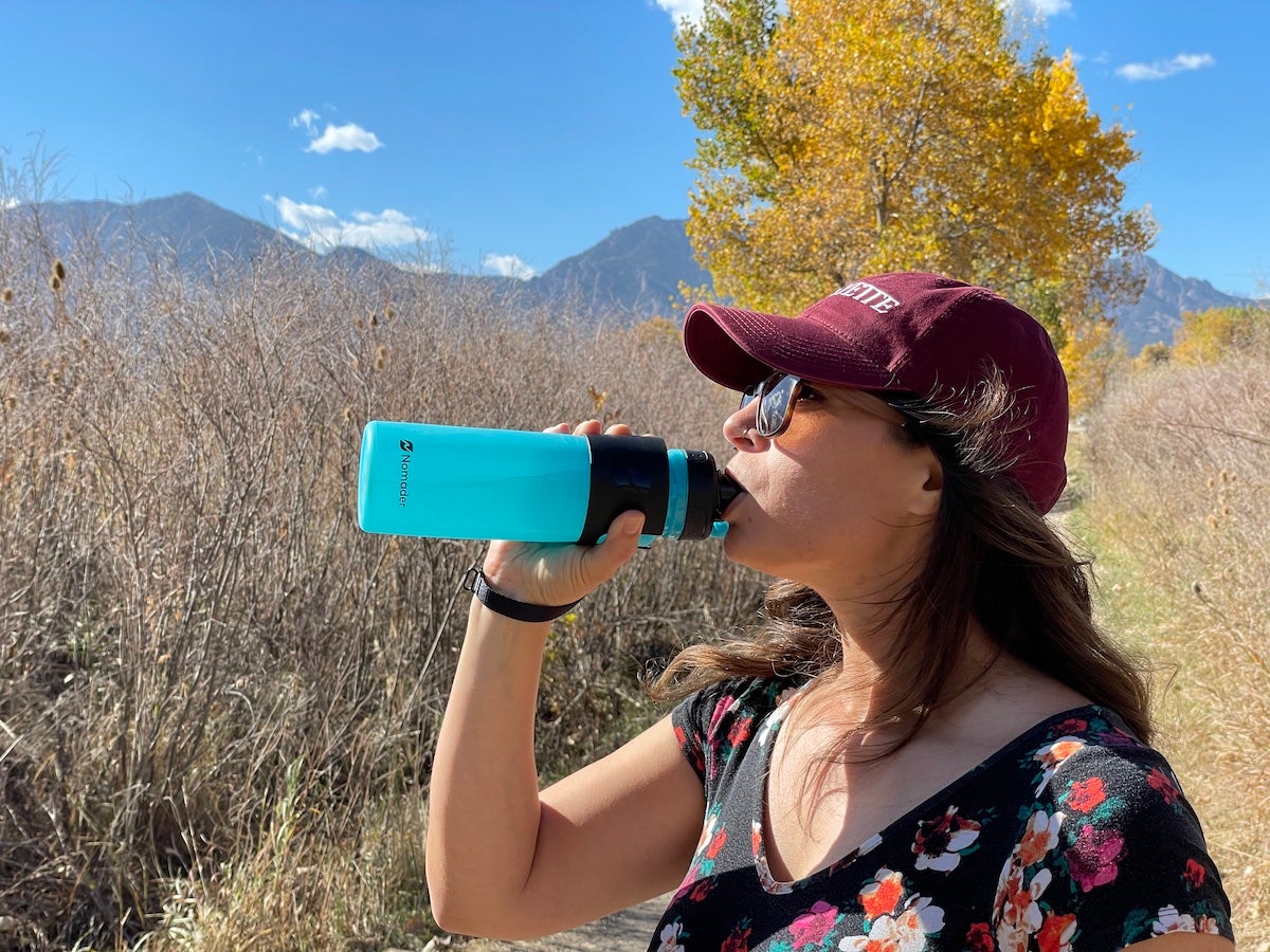 Female hiker drinking from Nomader Collapsible Water Bottle