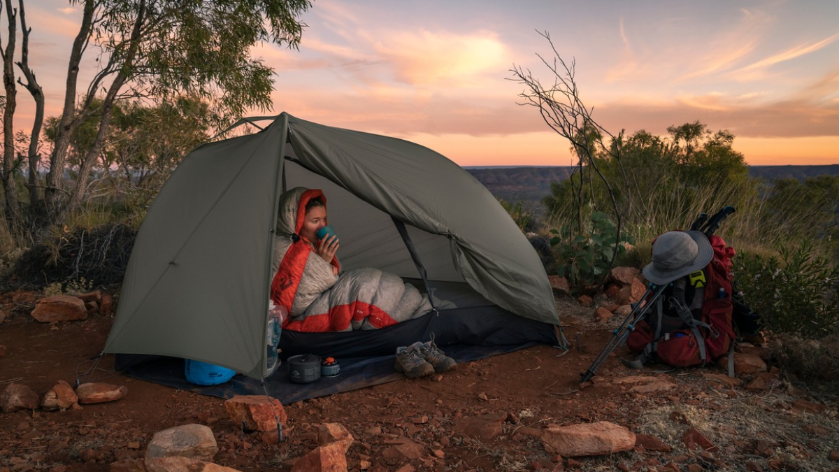 Female camper sipping coffee in Sea to Summit tent and sleeping bag
