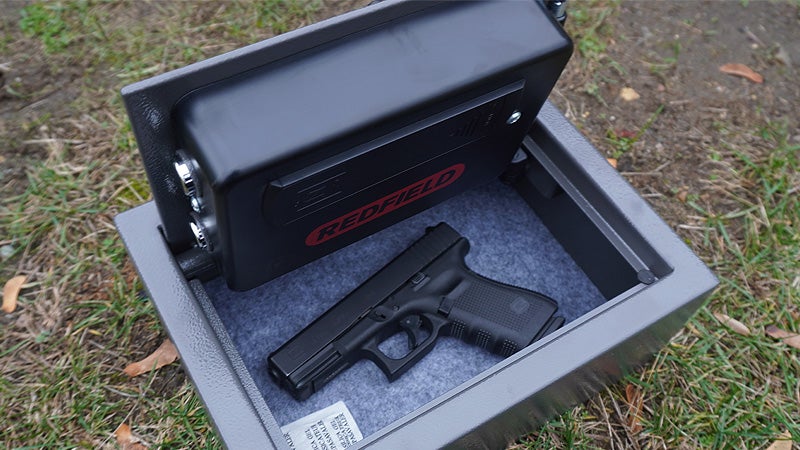 The interior of a Redfield Drawer Pistol lock box with a Glock pistol inside on a grassy lawn. 