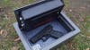 The interior of a Redfield Drawer Pistol lock box with a Glock pistol inside on a grassy lawn. 
