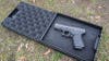 A black pistol box open showing a Glock 19 inside while sitting on a grassy lawn. 