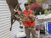 Hunter in his back yard shows off the rack of his buck, which hangs from a meat pole.