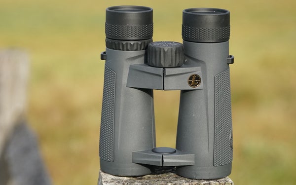 Leupold Santiam 10x42 binocular siiting on fence post with field in background.