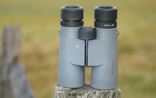 Tract Toric UHD 10x42 binocular sitting on fence post with field in background