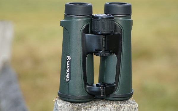 Vanguard 10x42 binocular sitting on fence post with field in background