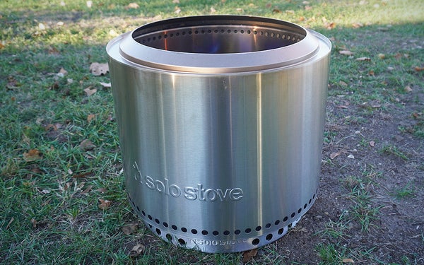 The Silver Solo Stove Bonfire 2.0 fire pit sitting in the shade on a grassy lawn.