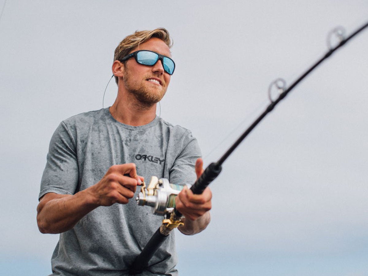 Man wearing Oakley Sunglasses while reeling in a fish