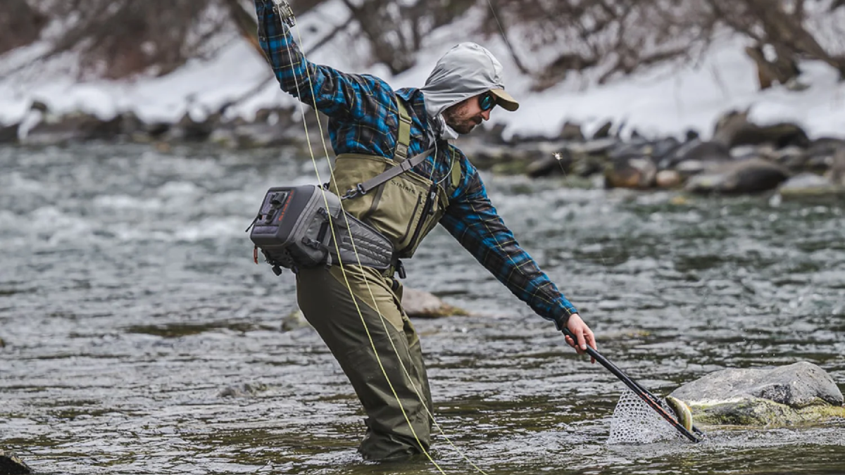 Angler catching trout wearing Simms Stockingfoot Fishing Waders