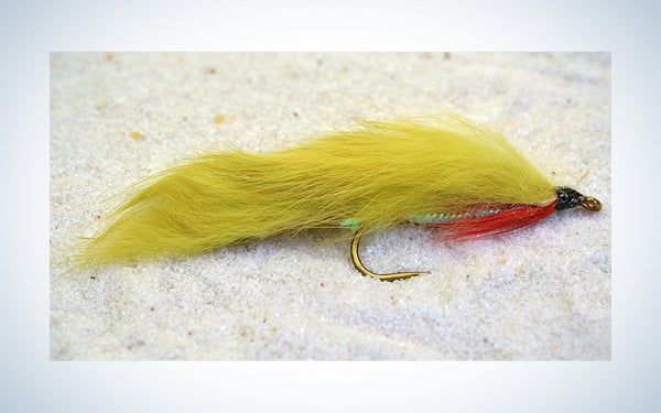 A green zonker streamer fly for trout fishing shown on a gradient background