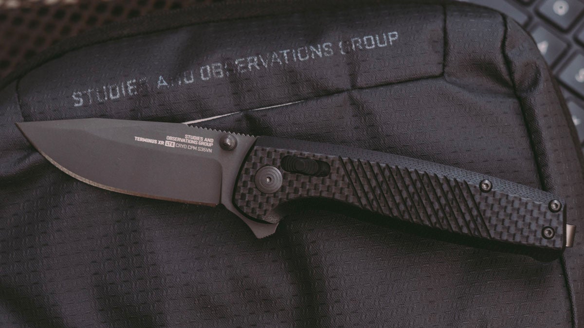 A black SOG knife sitting on black fabric.