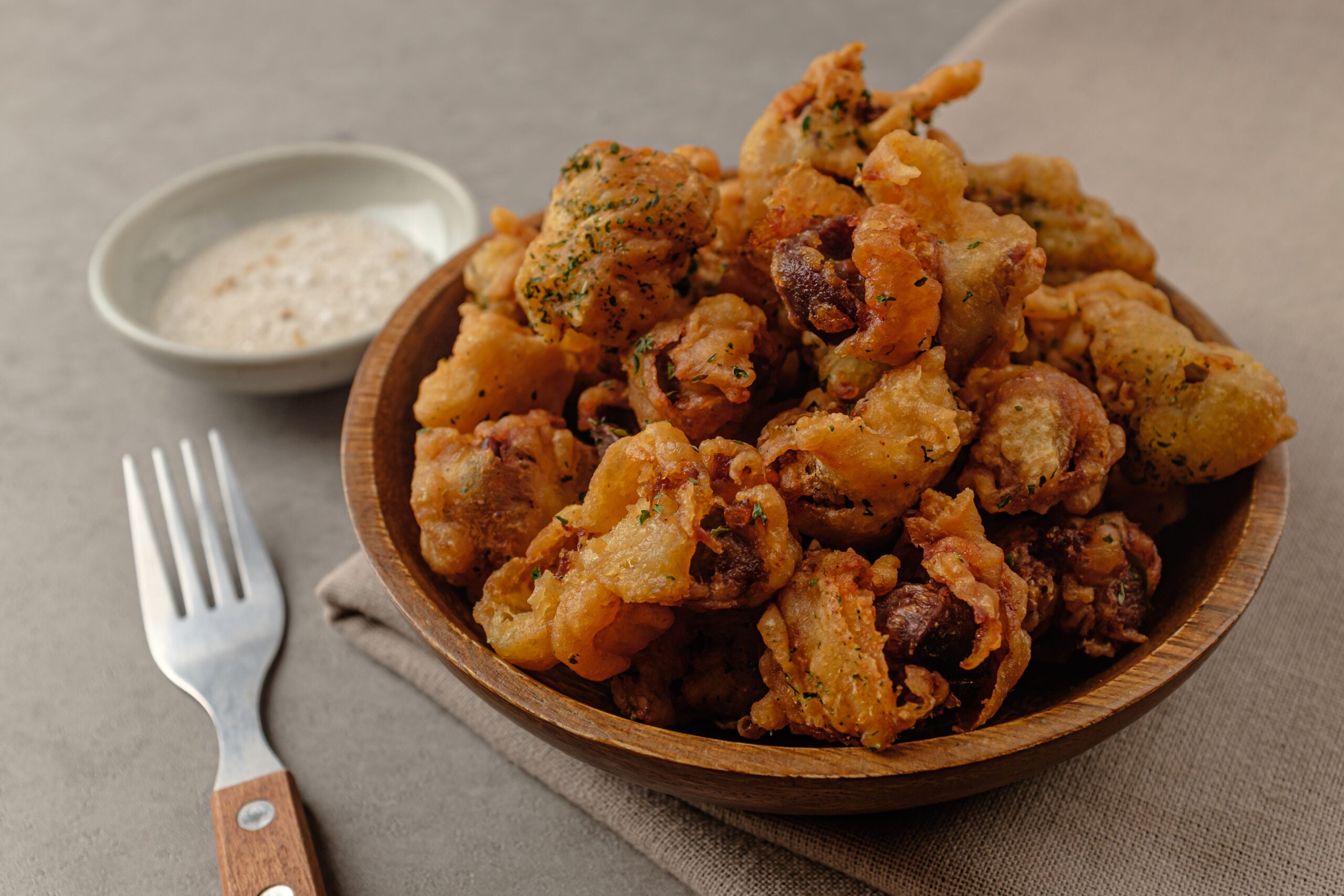 Seasoned and fried chicken gizzards served in a wooden bowl