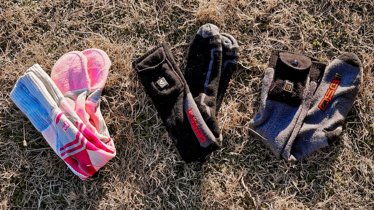 Three pairs of heated socks laying on the grass