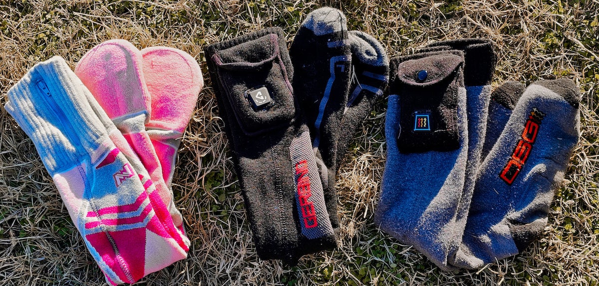 Three pairs of heated socks lined up on the grass