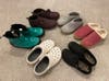 Six pairs of indoor outdoor slippers arranged on carpet