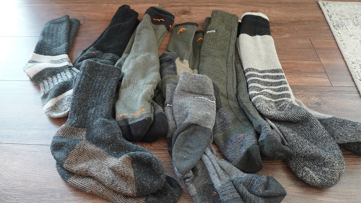 Several pairs of multi-colored hunting socks sitting on a hardwood floor.