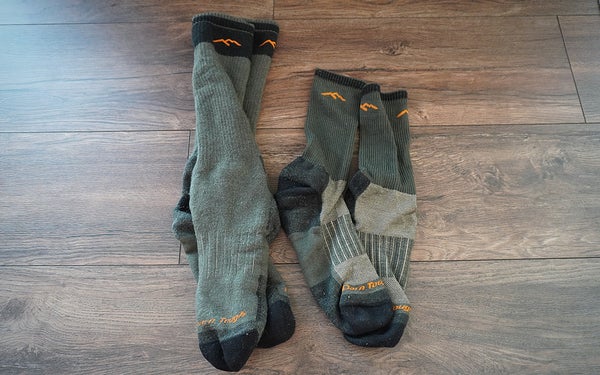 Two pairs of Darn Tough hunting socks sitting on a wooden floor.