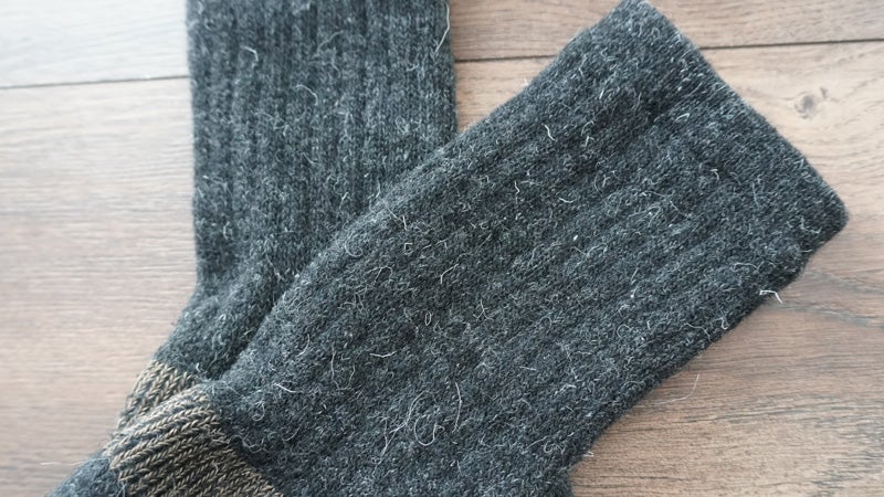 A close-up of the material of some GoWith Alpaca wool socks on a hardwood floor. 