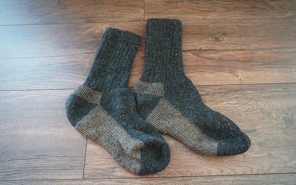 A pair of dark GoWith Alpaca wool hiking socks on a wooden floor.