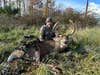 Hunter Ryan Grover sits in a field, posing with a huge whitetail buck he took with a bow