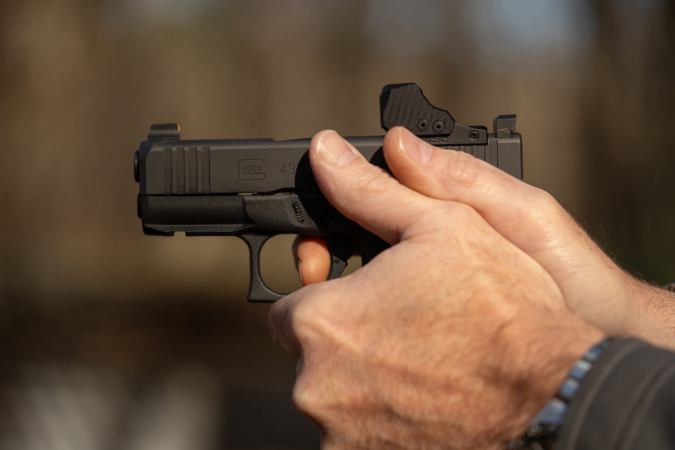 Closeup of man's hands firing a pistol, illustrating the proper grip and trigger finger position