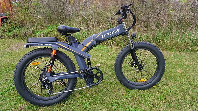 The grey and orange Engwe X24 bike sitting on a grassy lawn. 