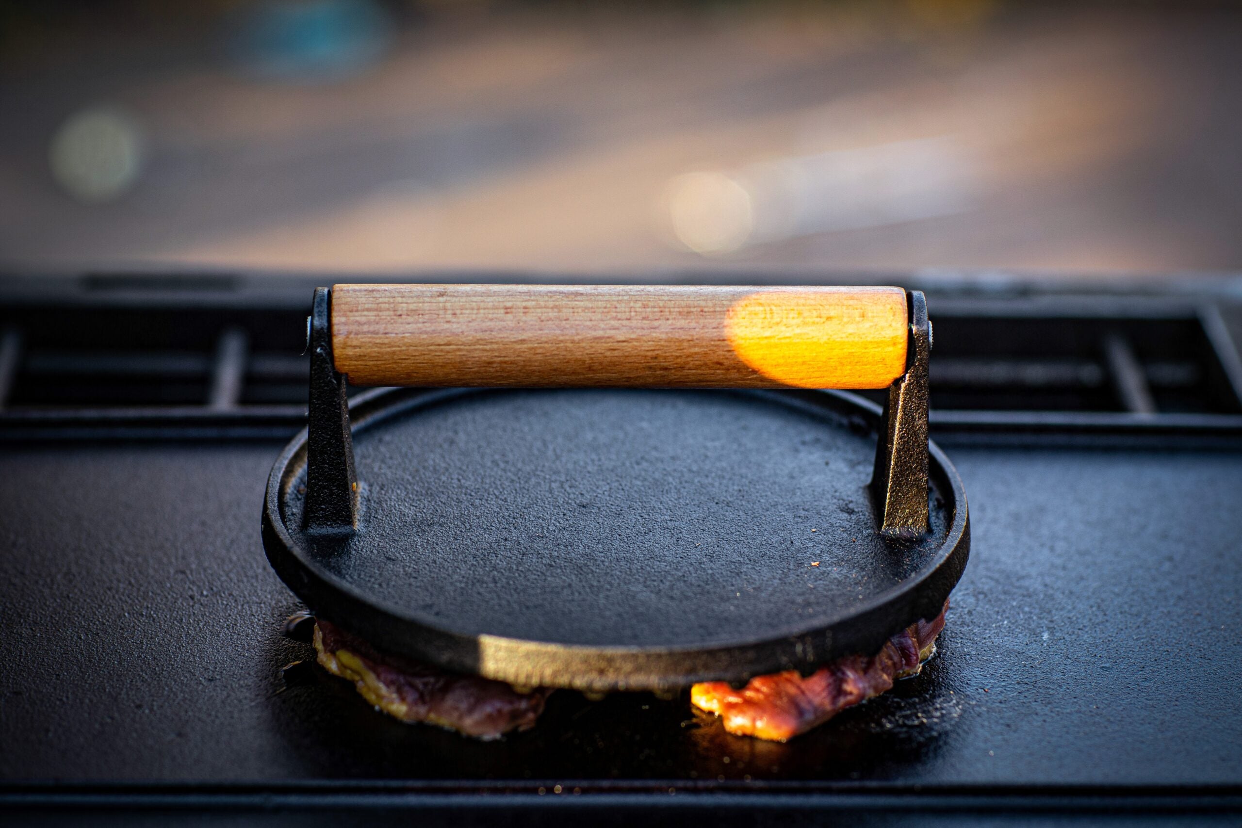 A duck breast cooks on cast iron beneath a cooking weight.