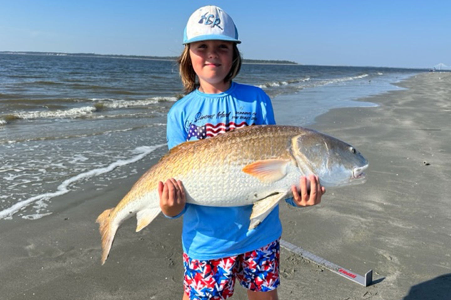 A youth angler poses with a record-setting red drum on St. Simons Island, Georgia.