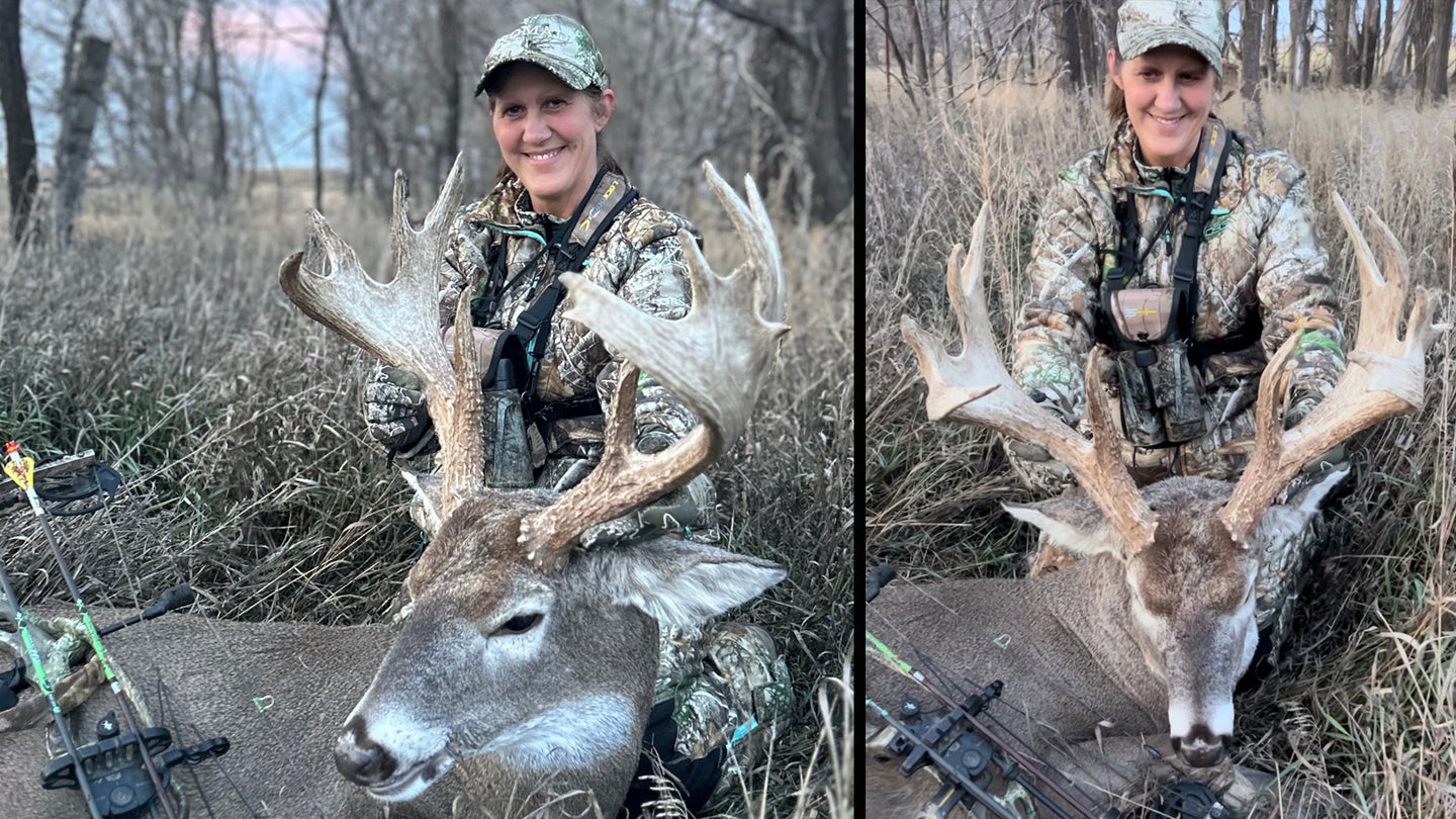 Woman sits on the ground and poses with a huge whitetail buck